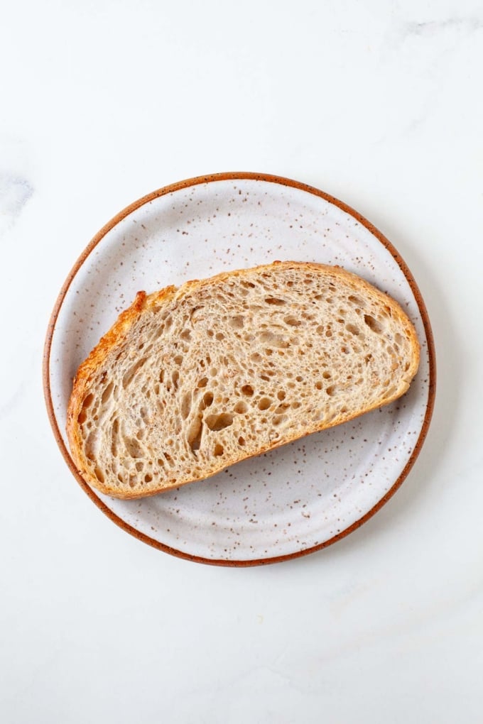 piece of wheat sourdough bread toasted on speckled grey plate