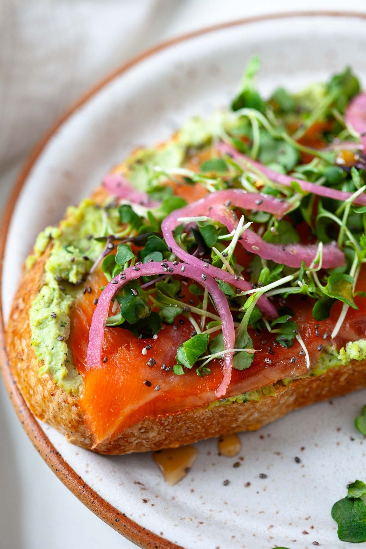 smoked salmon on sourdough slice with smashed edamame, pickled onion, microgreens and chia seeds