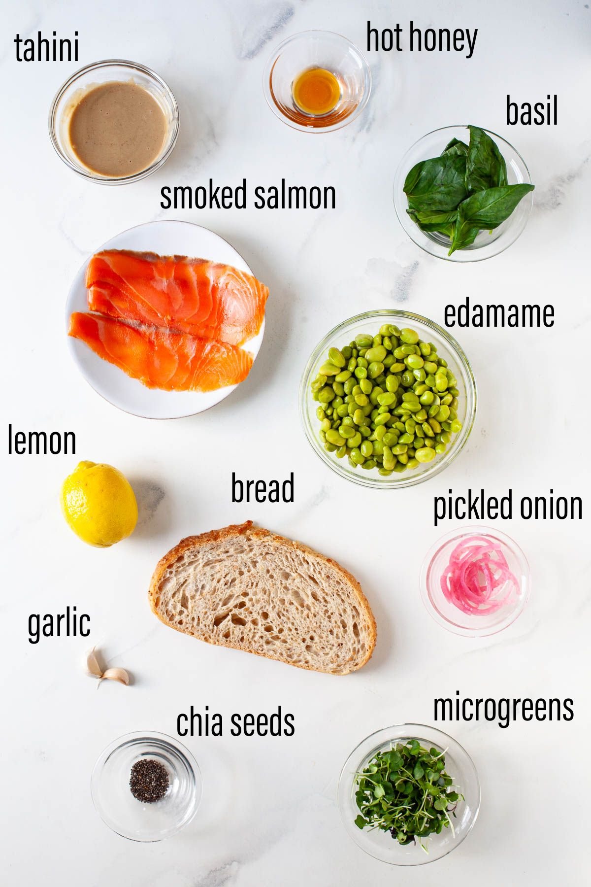 ingredients for smashed edamame toast with smoked salmon with black text overlay on white marble board